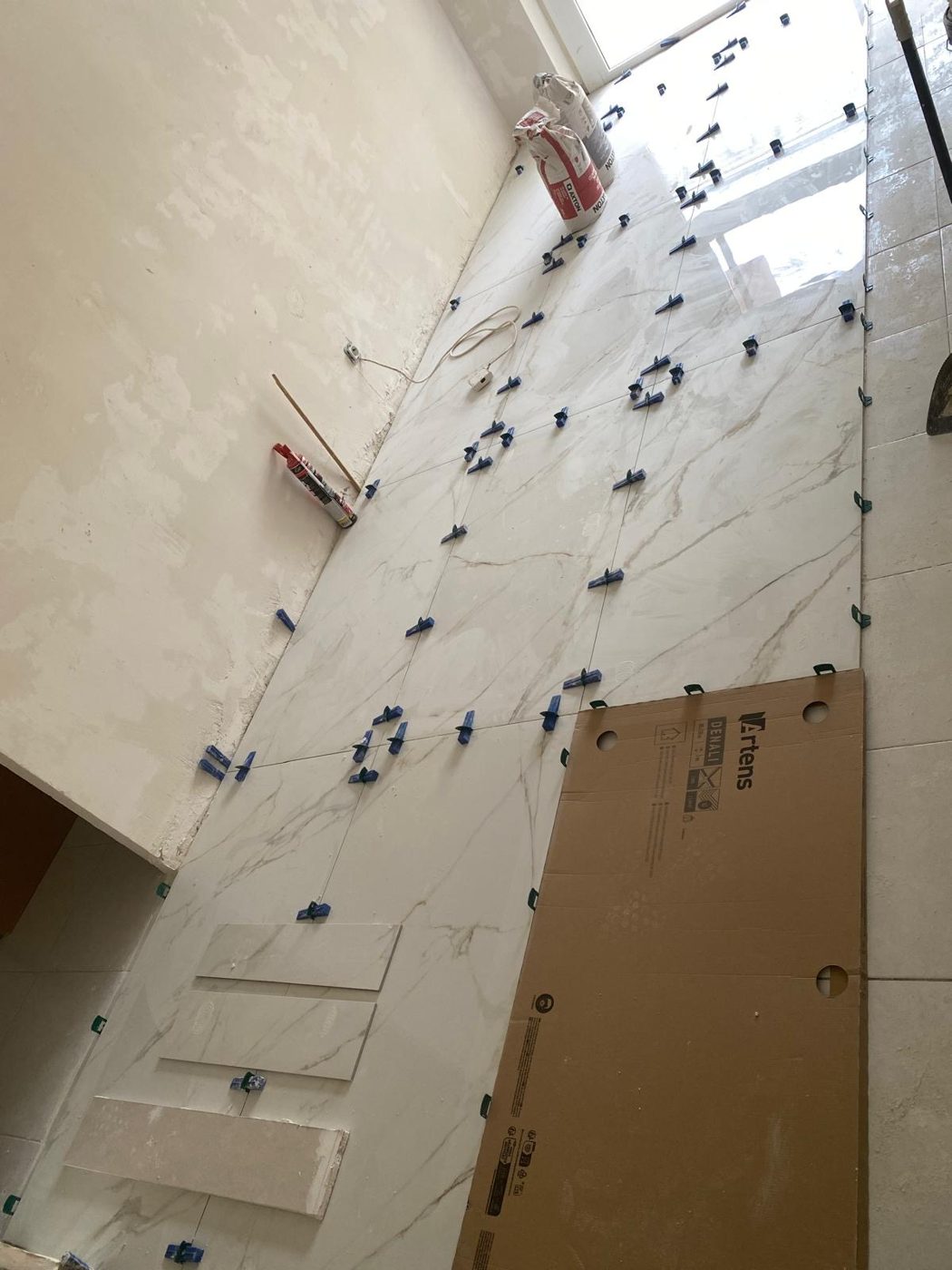 Sol carrelé en cours de pose, avec mise à niveau des carreaux